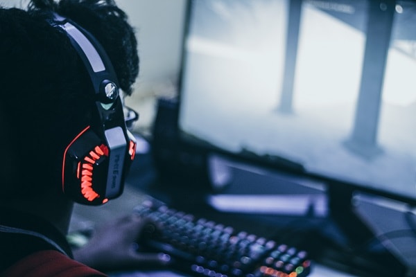 guy with headset in front of gaming screen