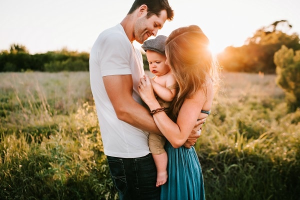 father and mother holding baby outside 