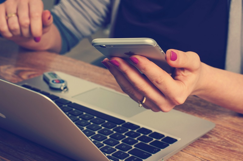 woman on phone in front of laptop